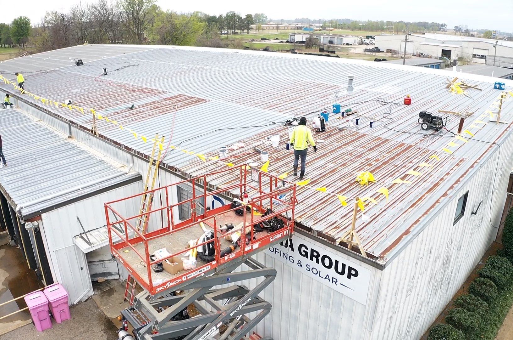 Commercial building with roofing professionals performing a roof replacement on a low-slope roofing system.